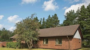 A single-story brick house with a tiled roof, surrounded by a grassy yard and trees. - 6 Person Holiday Home in NÃ¸rre Nebel (Norre Nebel)