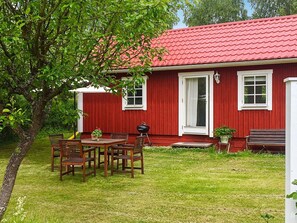 A red house with a white door, a small porch, and a table with chairs. - 4 Person Holiday Home in Stenhamra (Stenhamra)