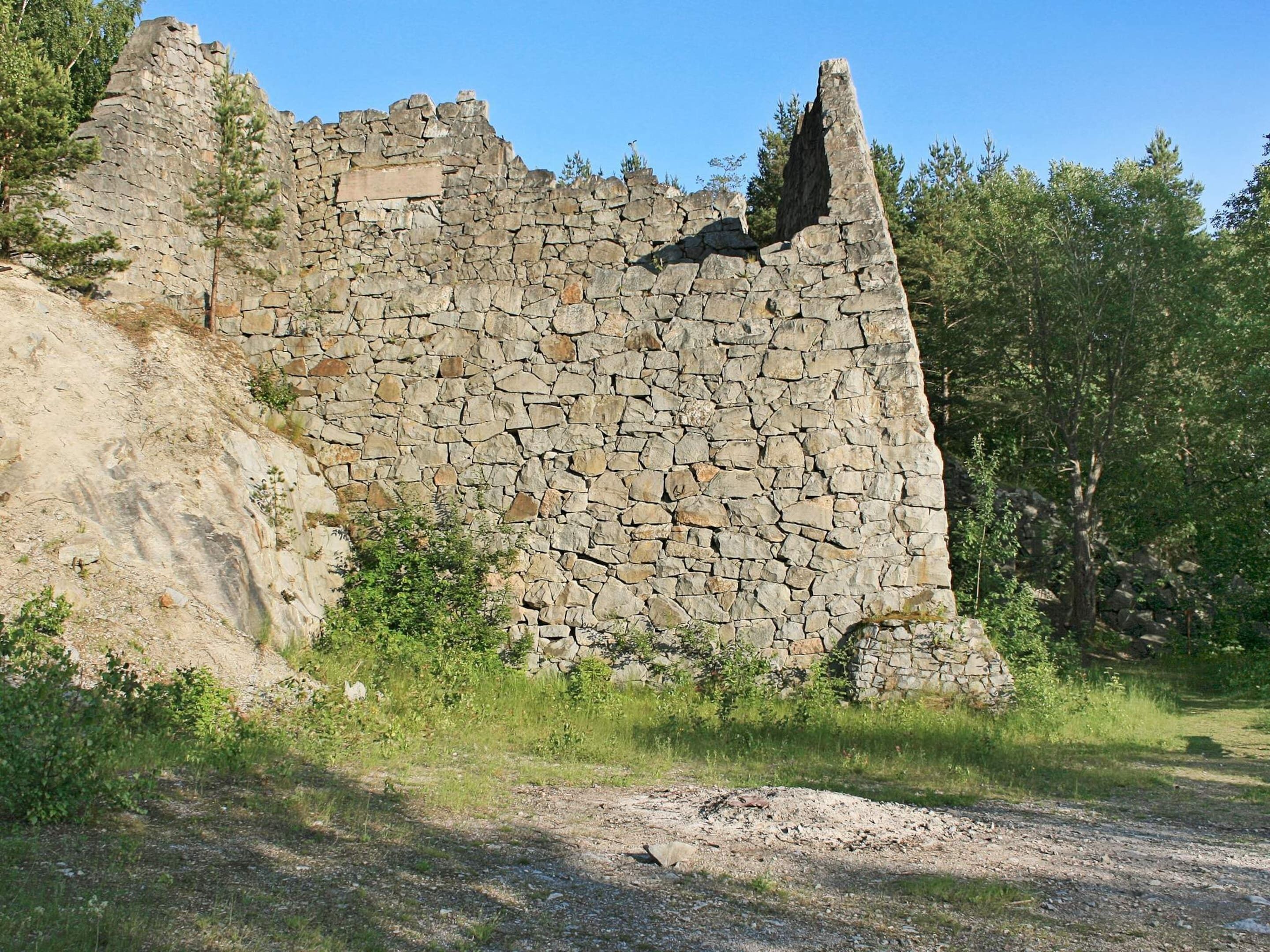 A stone ruin with a steep, uneven wall and a narrow passageway.