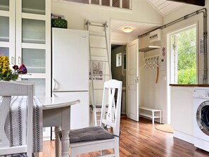 A compact kitchen with a refrigerator, a washing machine, and a dining area with a table and chairs. - 4 Person Holiday Home in Stenhamra (Stenhamra)