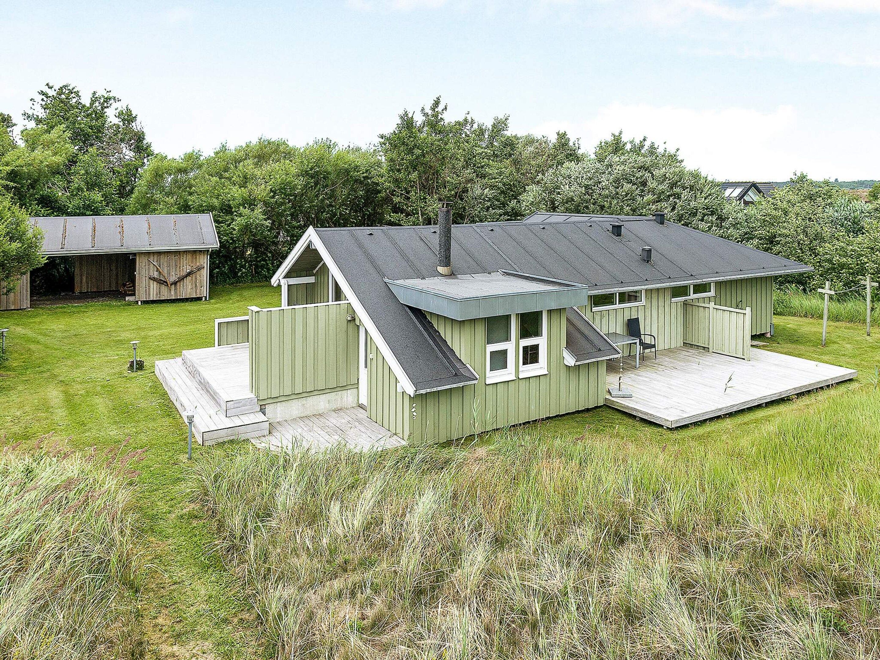 A green single-story house with a porch, a small deck, and a garage.