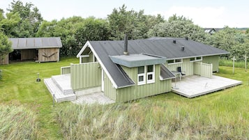 A green single-story house with a porch, a small deck, and a garage.