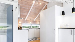 A modern kitchen with white cabinetry, a black countertop, and pendant lighting.
