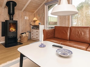 Ein gemütliches Wohnzimmer mit Kamin, Ledersofa und einem Tisch mit Schale und Fernbedienung.