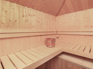 Un sauna avec des bancs en bois et un seau en bois.