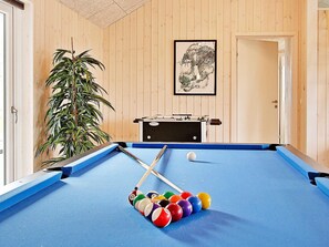 A pool table with balls, a foosball table, and a potted plant in a room with wooden walls. - Holiday Home in Kappeln (Kappeln)