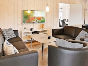 A modern living room with a sofa, a coffee table, and a TV mounted on the wall. - Holiday Home in Kappeln (Kappeln)