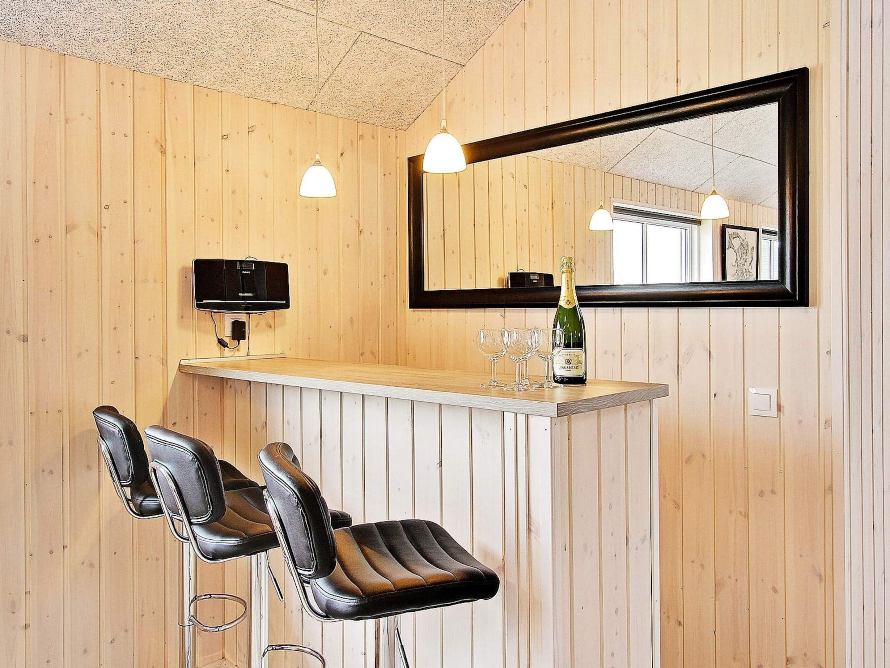 A bar area with wooden paneling, a large mirror, two bar stools, a bottle of champagne, and two glasses.
