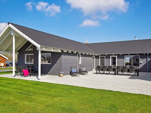 Un bâtiment doté d’un patio couvert, d’un espace extérieur aménagé pour s’asseoir et d’une pelouse.