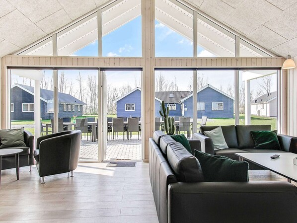 A spacious indoor area with a high ceiling, large windows, and a view of residential buildings. - Holiday Home in Kappeln (Kappeln)