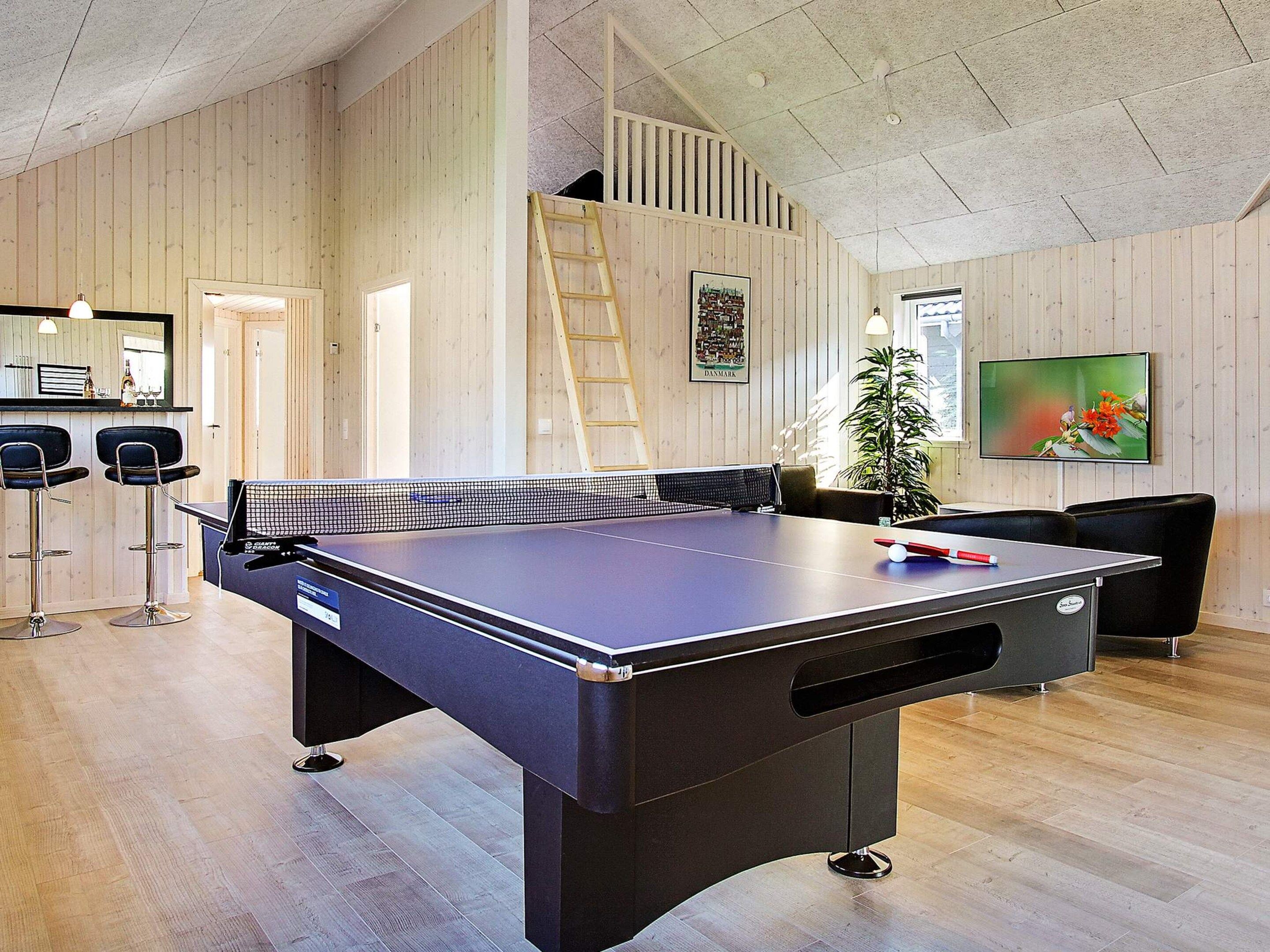 A ping pong table in a room with wooden walls and a ceiling with exposed beams.