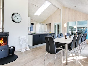 A modern kitchen with a central island, a dining area with a long table and chairs, and a visible clock on the wall. - Holiday Home in Kappeln (Kappeln)