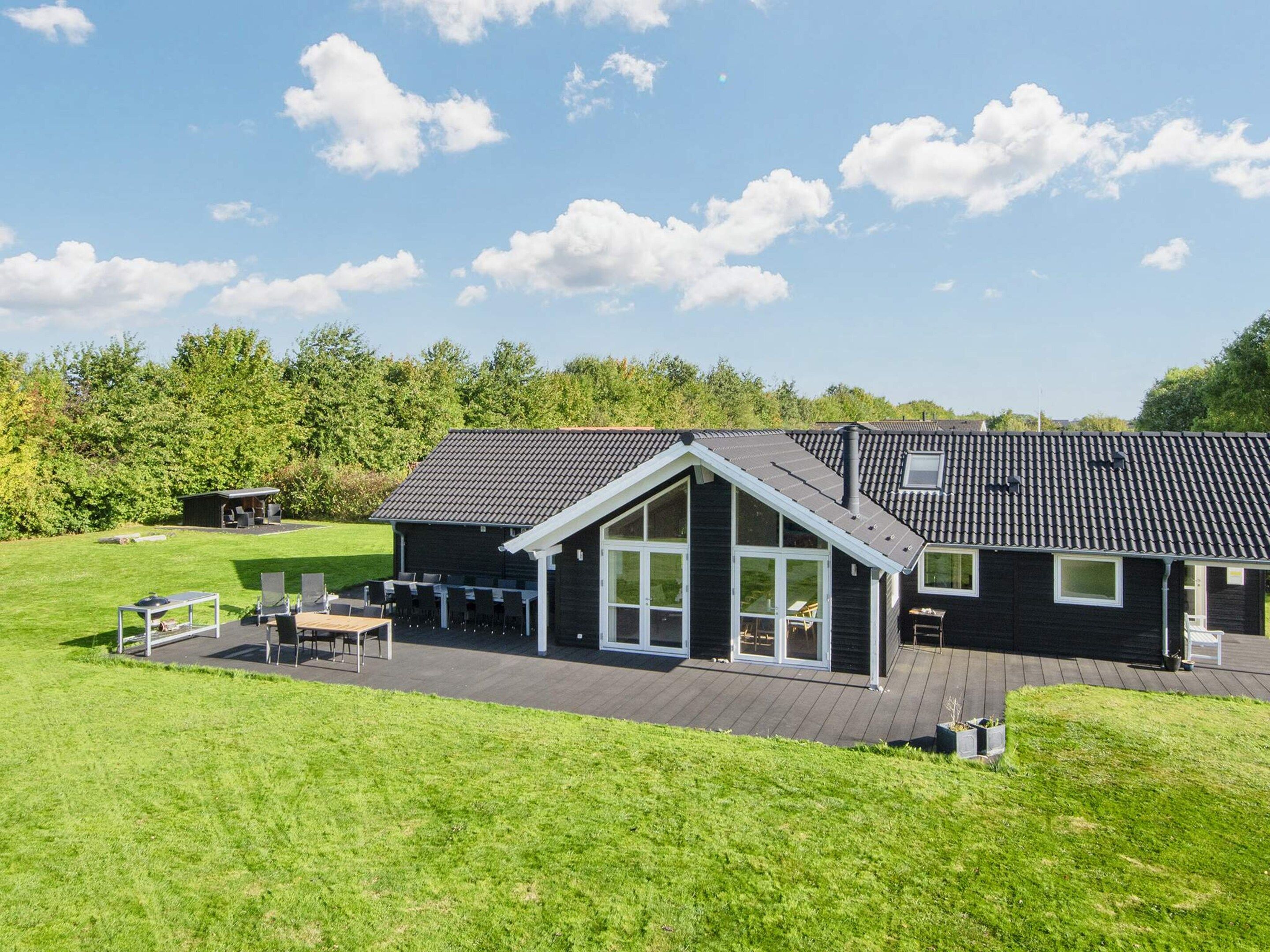 A modern house with a large deck, a covered outdoor seating area, and a well-maintained lawn.