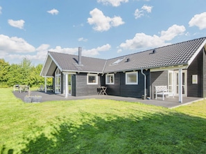 Une maison moderne à deux étages, dotée d’un patio couvert, d’une cheminée et d’une pelouse bien entretenue.