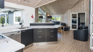 A modern kitchen with a central island, a dining area with a table and chairs, and a cozy seating area with sofas. - 5 Star Holiday Home in Sydals (Sydals)
