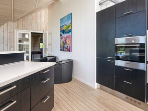 Une cuisine moderne avec des meubles de couleur sombre, un plan de travail blanc et un four de la marque Bosch.