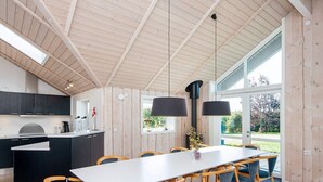 A modern kitchen with a central island, wooden flooring, and large windows offering a view of the outdoors. - 5 Star Holiday Home in Sydals (Sydals)