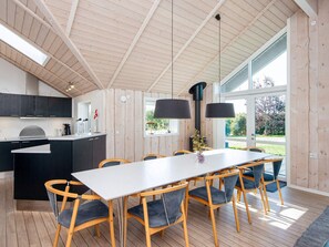 Une cuisine moderne dotée d’un îlot central, de planchers en bois et d’un coin repas avec une longue table et des chaises.
