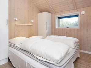 Une chambre à coucher comprenant un lit, une armoire, une fenêtre et des lampes fixées au mur.