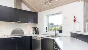 A modern kitchen with dark cabinetry, a white countertop, and a window providing natural light. - 5 Star Holiday Home in Sydals (Sydals)
