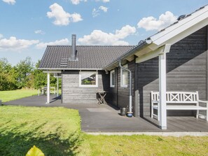 A wooden house with a covered porch, a chimney, and a small window. - 5 Star Holiday Home in Sydals (Sydals)
