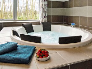 Ett spa-rum med ett bubbelbad, handdukar och en skål med jordgubbar.