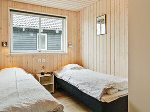 A room with two beds, a window, a small table, and a wall-mounted picture. - Holiday Home in Kappeln (Kappeln)