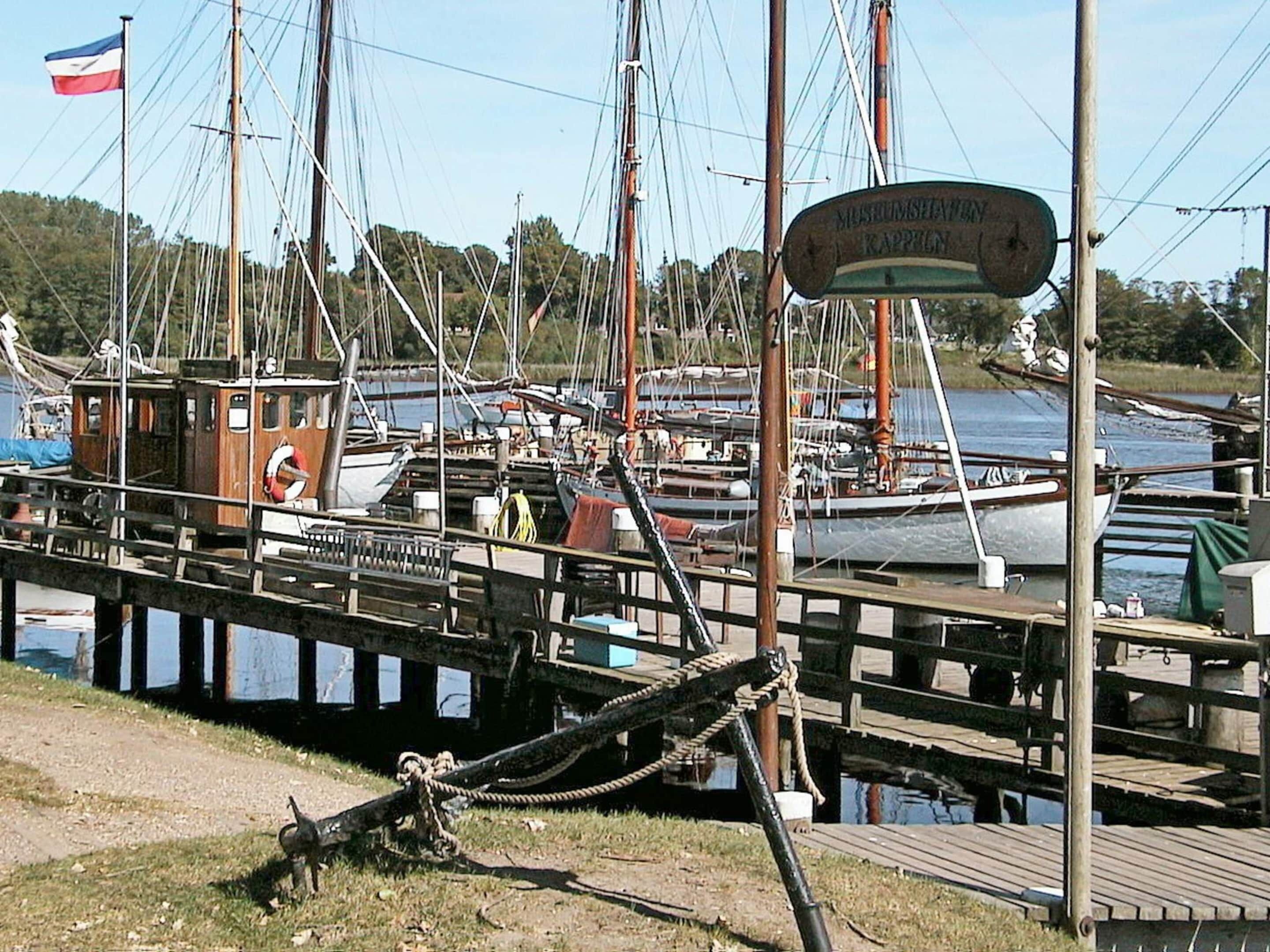 A marina with docked boats, a wooden pier, and a sign indicating a museum.