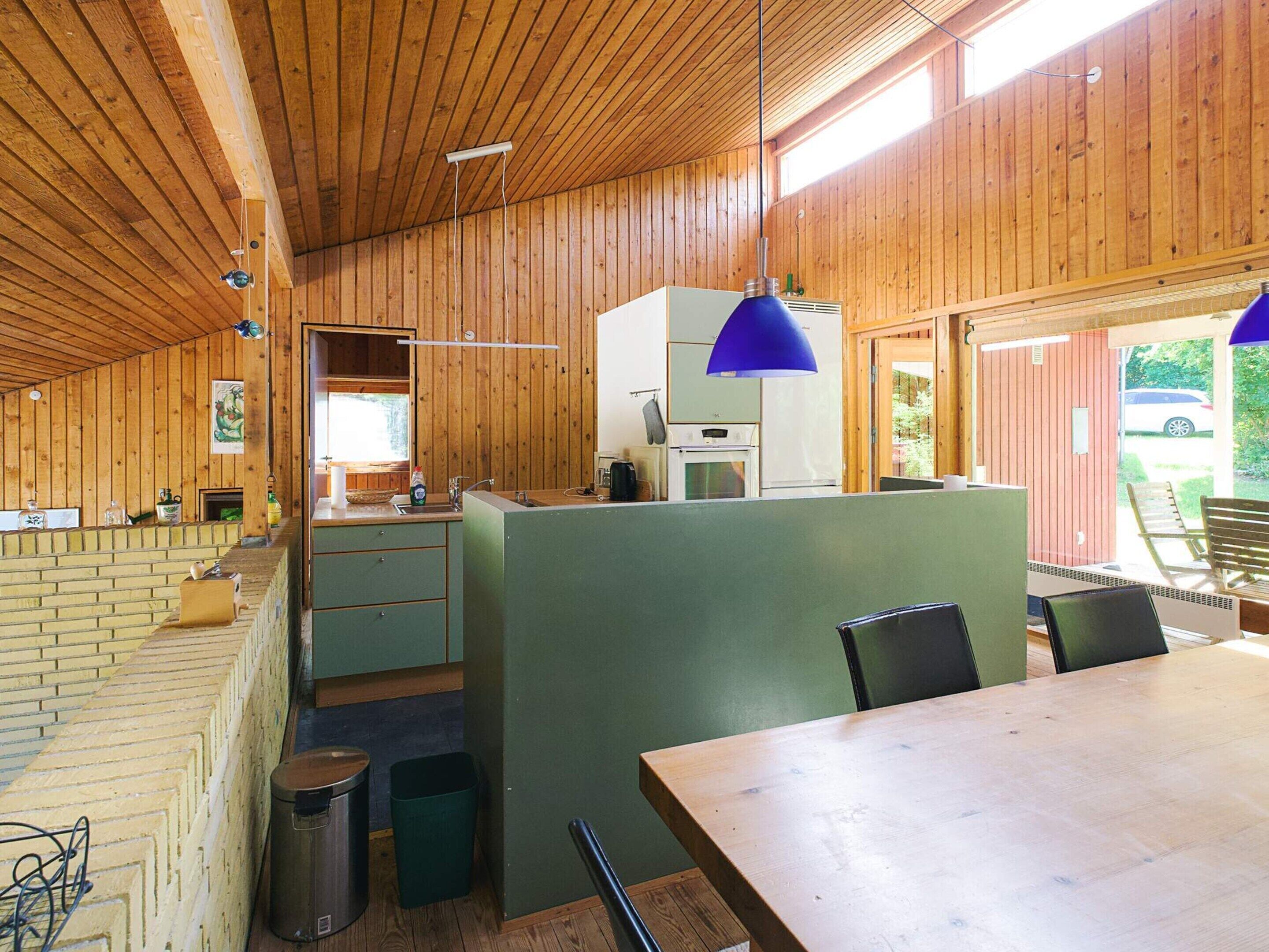 A wooden interior with a kitchen, dining area, and a view of the outside.