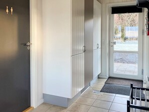A hallway with white cabinets, a door with a window, and a bench. - 4 Star Holiday Home in Spottrup (Spøttrup)