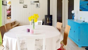 Un comedor con una mesa redonda, sillas, un florero con flores amarillas y un mueble azul.
