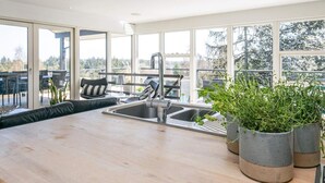 A modern kitchen with a large window, a sink, and a dining area with outdoor seating.