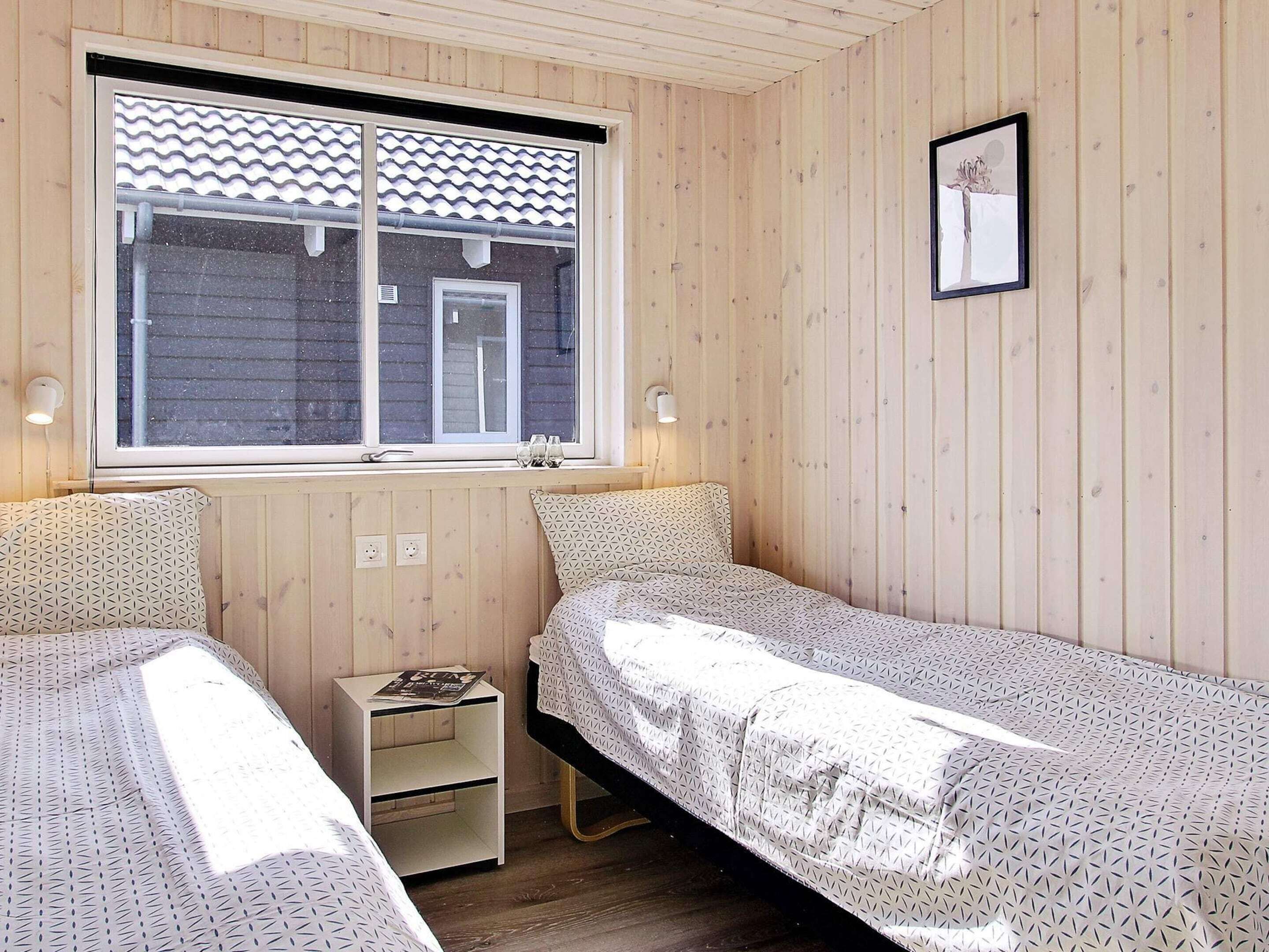 Ein Zimmer mit zwei Einzelbetten, einem Fenster mit Aussicht, einem kleinen Nachttisch und einem Wandbild.
