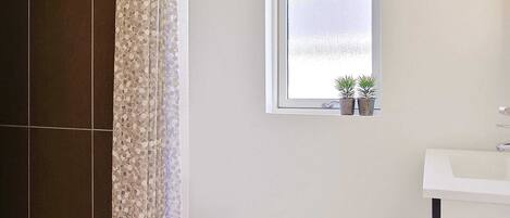 A bathroom with a window, a sink, and two potted plants.