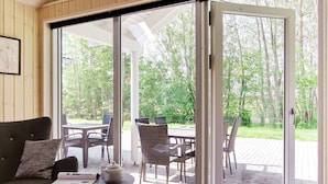 Une pièce dotée d’une porte-fenêtre coulissante donnant sur un patio extérieur avec une table et des chaises.