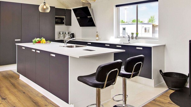 A modern kitchen with a central island, bar stools, a large window, and pendant lighting. - Holiday Home in Kappeln (Kappeln)