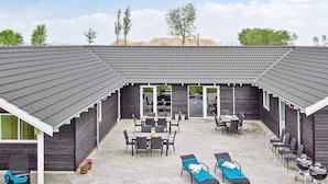 A building with a patio area featuring outdoor furniture, a grill, and a covered seating area. - Holiday Home in Kappeln (Kappeln)