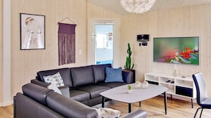 A modern living room with a sofa, coffee table, TV, and a cactus plant. - Holiday Home in Kappeln (Kappeln)