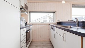 Une cuisine moderne avec des murs recouverts de panneaux en bois, une fenêtre offrant une belle vue, des appareils en acier inoxydable et un plan de travail noir.