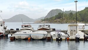A marina with several boats docked, a small cabin, and a mountainous landscape in the background.