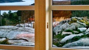 A view through a window with a rocky landscape and a body of water in the distance.