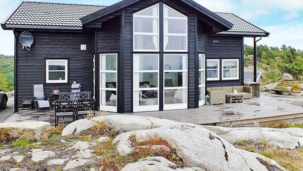 A modern black house with large windows and a patio area.