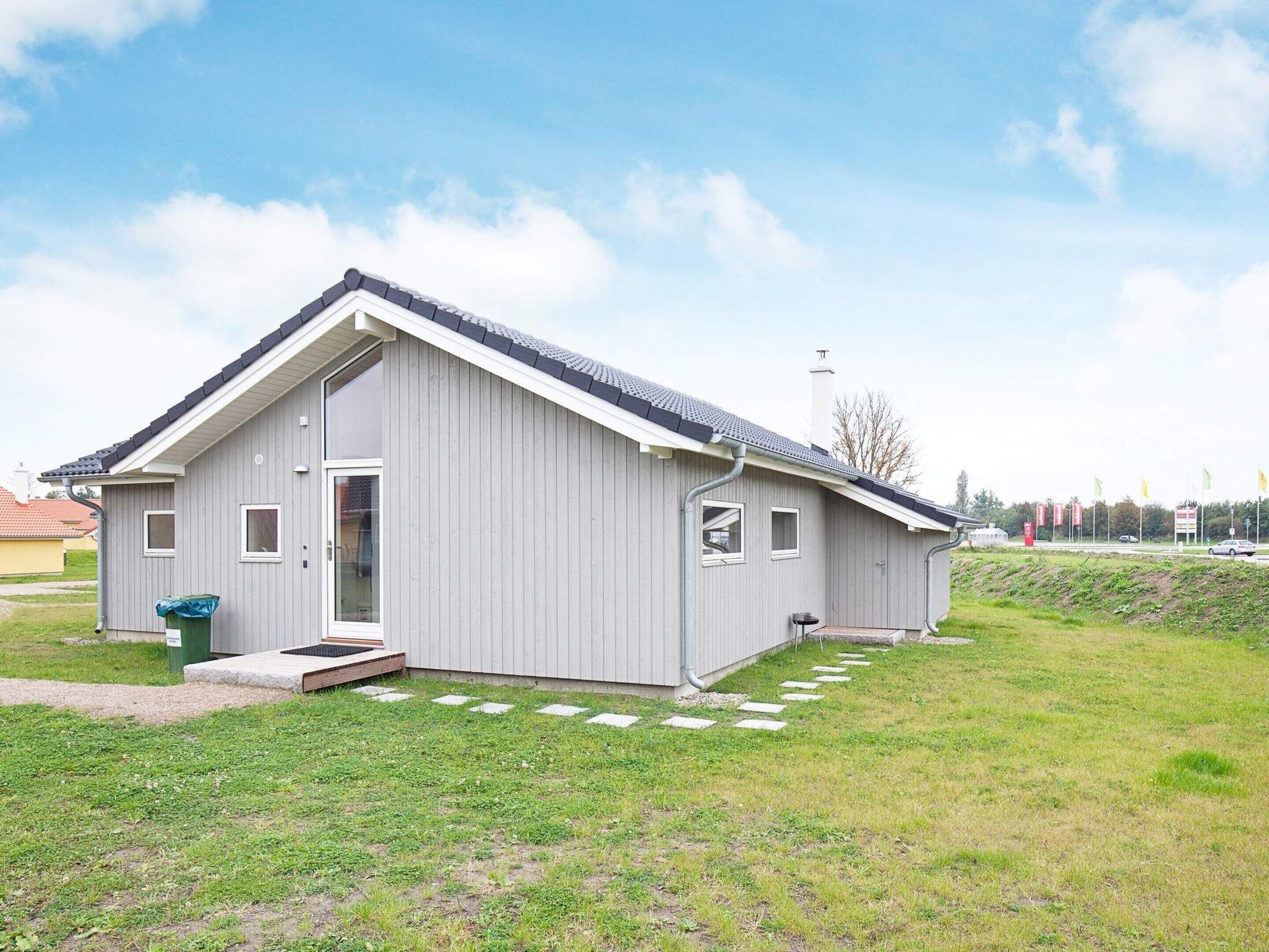 A modern single-story building with a sloped roof, large windows, and a small porch area.