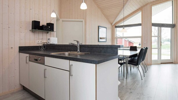 A modern kitchen with a central island, stainless steel sink, and pendant lighting. - Holiday Home in Großenbrode (Grossenbrode)
