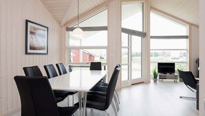 A conference room with a long table and black chairs, large windows, and a television in the corner. - Holiday Home in Großenbrode (Grossenbrode)