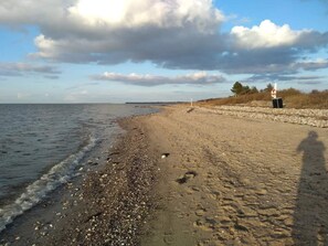 A beach with pebbles, a clear sky, and a distant horizon.