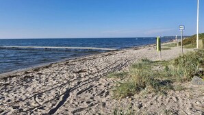Ein Strand mit einer Holzsteg, sandigem Ufer und einem WC-Schild.