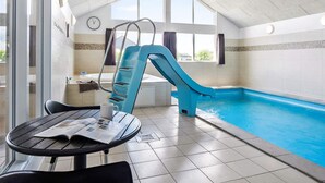 Ein Hallenbad mit einer blauen Rutsche, einer Uhr an der Wand und einem Tisch mit einer Zeitschrift.