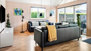 Ein modernes Wohnzimmer mit einer Couch, einem Fernseher und Kunstwerken an der Wand.