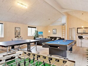 A recreational room with a foosball table, pool table, and a sofa.